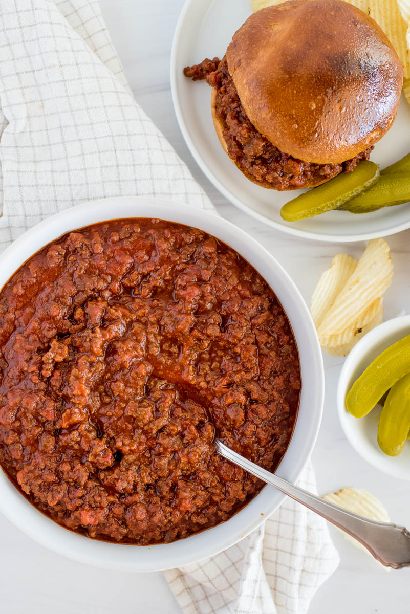 Instant Pot sloppy joe mix ready to serve in a white bowl, with a ready to eat sloppy Joe in the upper right and corner.