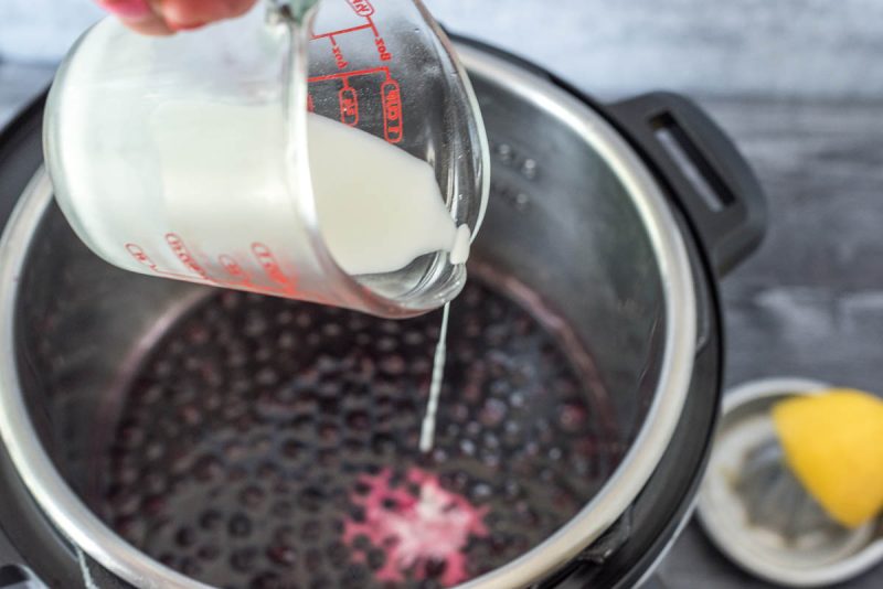 Adding cornstarch slurry to an Instant Pot to thicken blueberry compote.