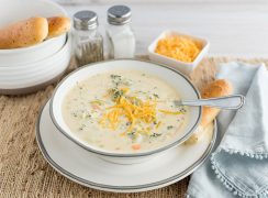Pressure Cooker Broccoli Cheese Soup, dished up and ready to serve with additional shredded cheese and breadsticks