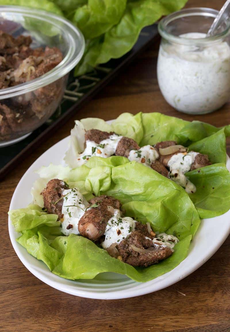 A Middle Eastern Chicken Shawarma, tender chunks of seasoned chicken thighs are served on lettuce leaves with Tzatziki sauce.