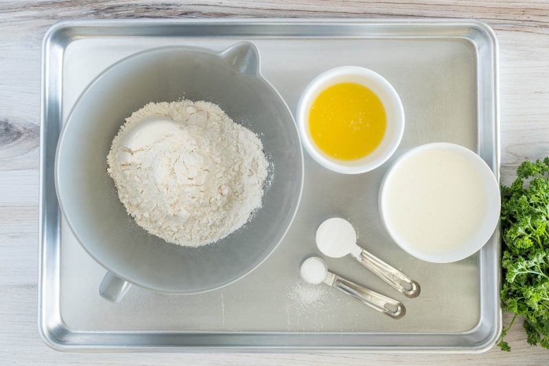 Overhead picture of the ingredients for homemade dumplings, including flour, salt, heavy cream, and melted butter.