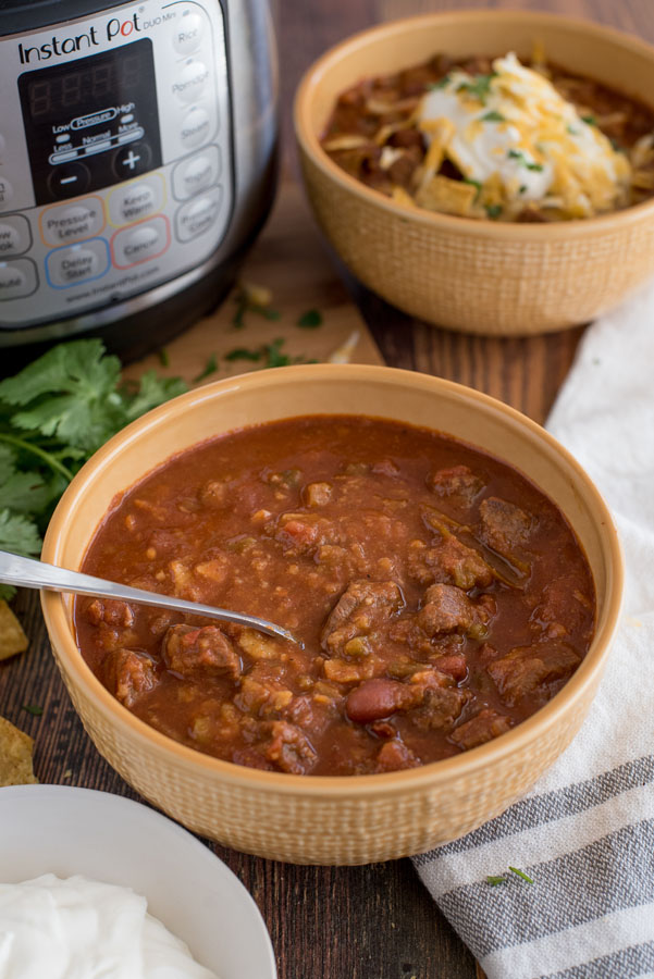 Instant Pot in the background of the Pressure Cooker / Instant Pot Beef and Bean Chili with cilantro and a second bowl of chilli in the background