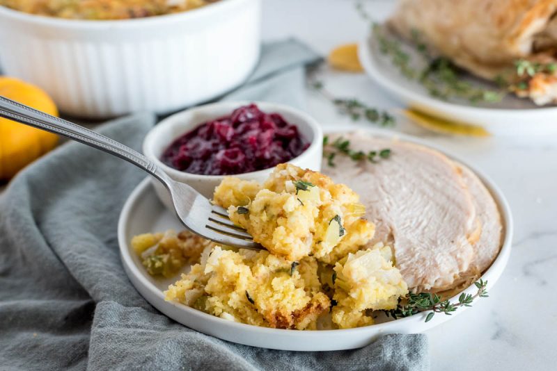 Instant Pot cornbread stuffing served on a plate with sliced turkey and cranberries with a fork.