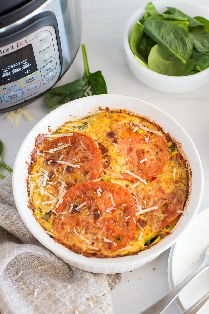 Close up of Instant Pot crustless spinach quiche topped with sliced tomatoes and placed in front of an Instant Pot