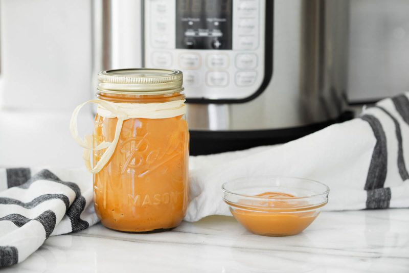 Dulce de leche in a bowl and in a mason jar and placed in front of an Instant Pot.