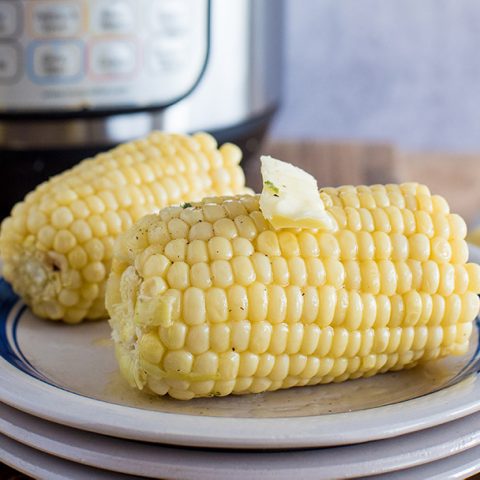Easy Pressure Cooker Corn on the Cob, plated with an Instant Pot in the background