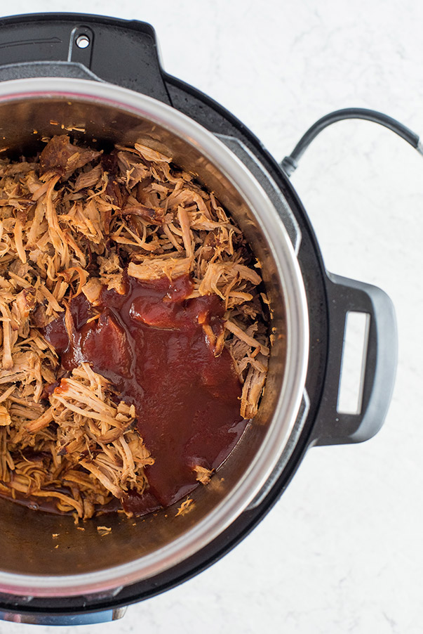Shredded pork in the Instant Pot with barbecue sauce drizzled on top