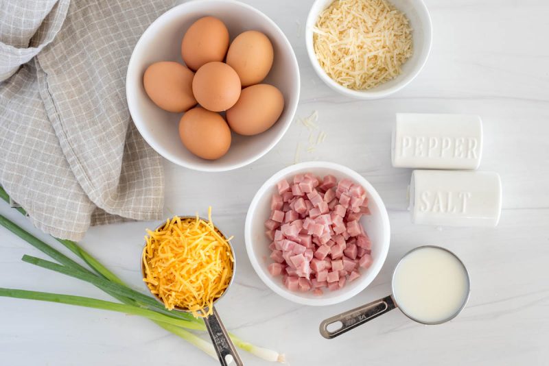 an overhead shot of the ingredients needed to make Ham and Cheese Quiche, with eggs, salt, pepper, cheese, parmesan,