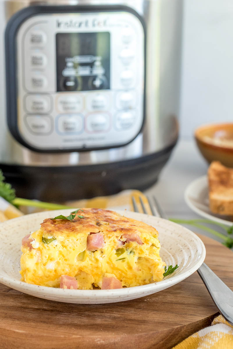 a small white plate of easy crustless quiche with eggs, ham, and cheese, in front of an Instant Pot