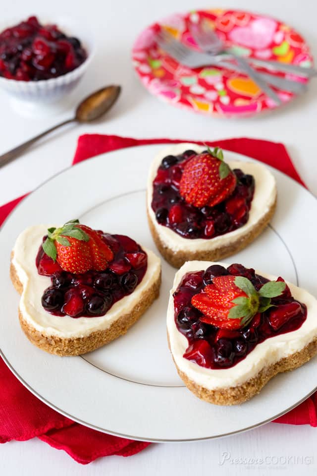 A heart shaped cheesecake is the perfect Valentine\'s Day dessert! Rich, creamy vanilla cheesecake with a graham cracker crust, in a fun heart shape. This decadent cheesecake is topped with a sweet triple berry sauce. One of the best pressure cooker cheesecake recipes that you can make for your Valentine.