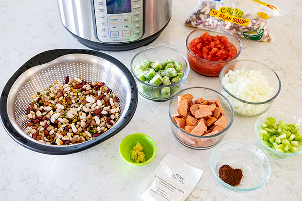 An Instant Pot in the background with, Cajun 15 beans mix, okra, sausage, celery, onion, and seasonings