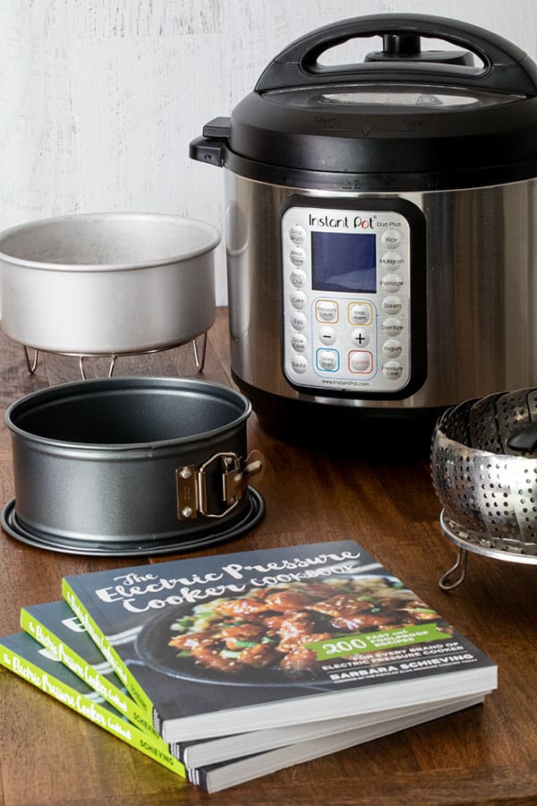 a photo showing a cake pan, tall trivet, cookbooks, and steamer basket with an Instant Pot Duo Plus