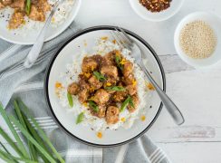 An overhead shot of Instant Pot Teriyaki Chicken, served with a fork and sesame seeds and red pepper flakes and green onions on the edges of the photo
