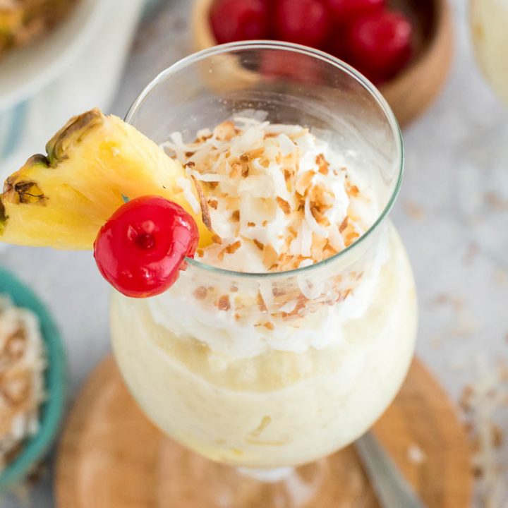 glass of coconut rice pudding with a pineapple and cherry on top