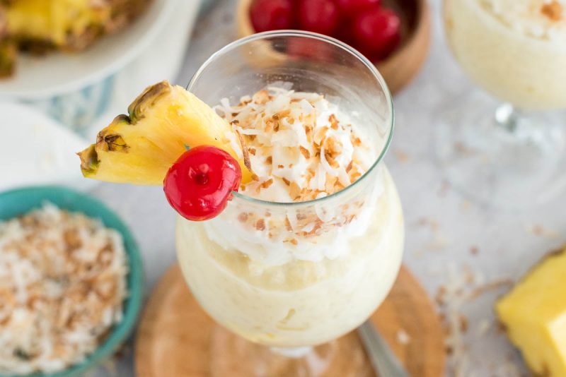 glass of coconut rice pudding with a pineapple and cherry on top