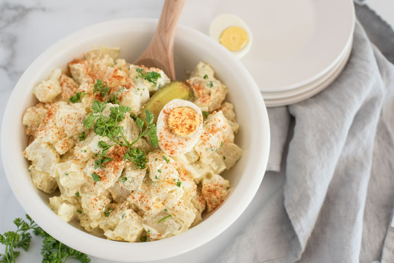 white bowl of Instant Pot potato salad with slices of hard boiled eggs in it