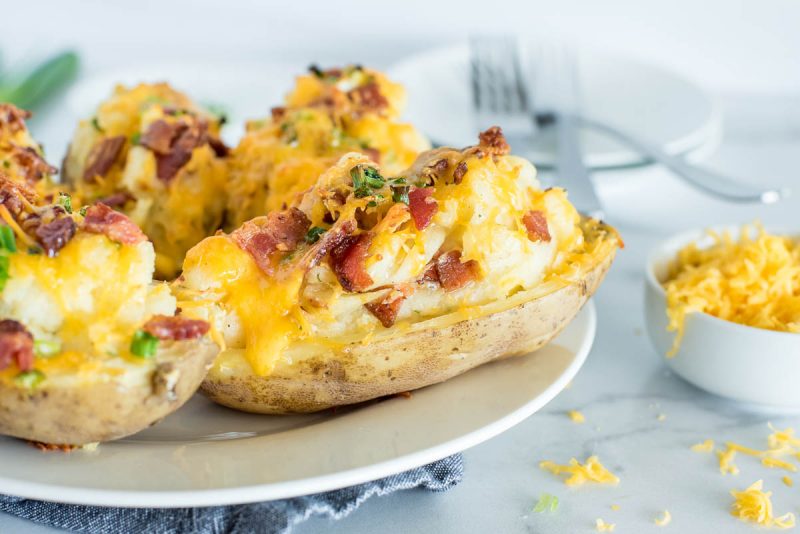 twice baked ranch potatoes on a white plate with bacon on top