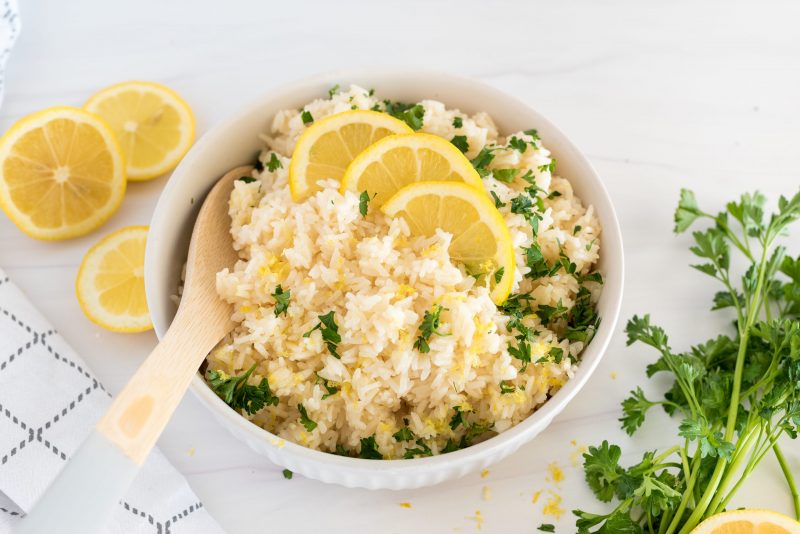 white bowl of instant pot lemon rice with a wooden spoon