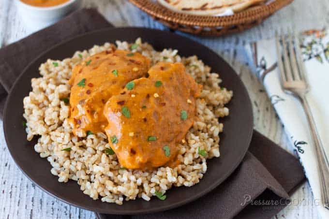 A plate of food with butter chicken over rice