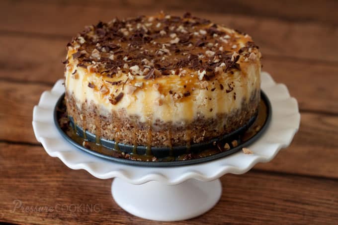 Pressure Cooker New York Cheesecake with a Toffee Pecan Shortbread Cookie Crust on a white cake stand