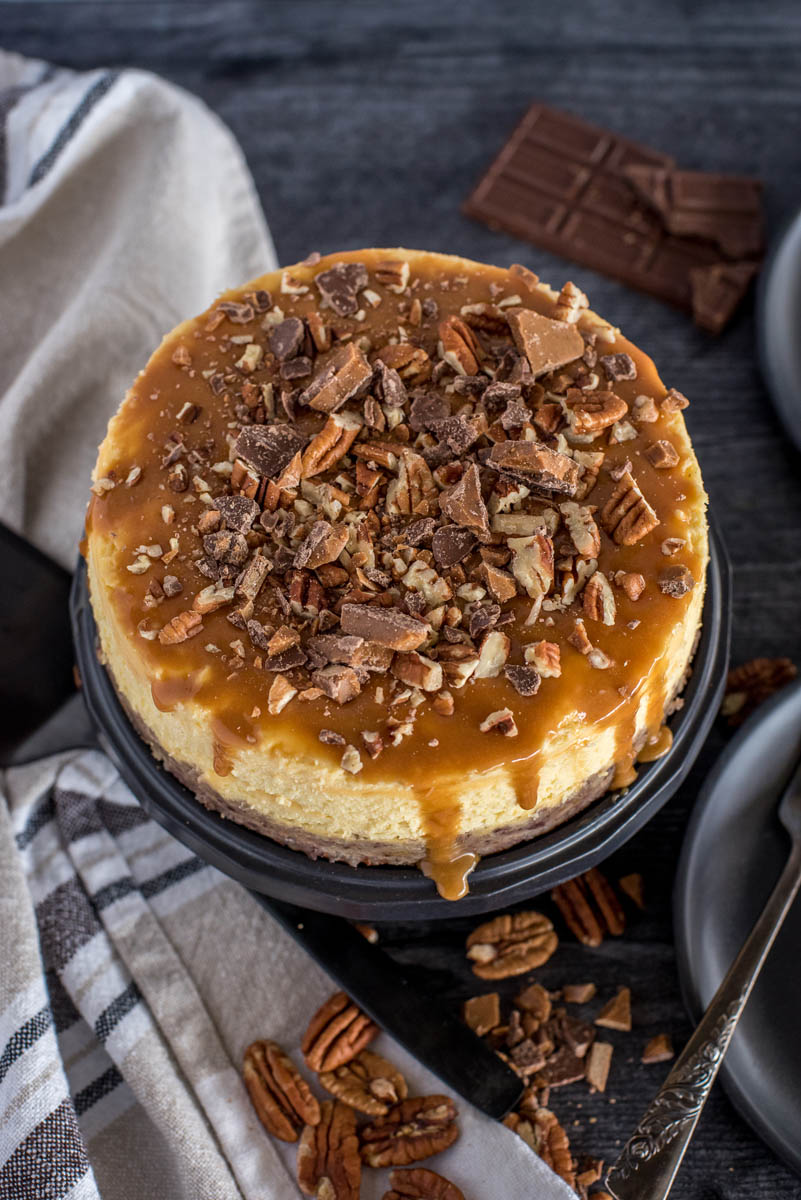 Overhead shot of an Instant Pot New York cheesecake topped with caramel, toffee, and pecans.