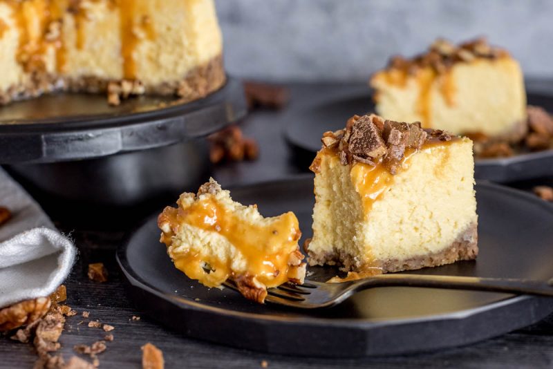 A fork taking a bite off of a piece of New York cheesecake that was made in an Instant Pot and topped with caramel and chocolate