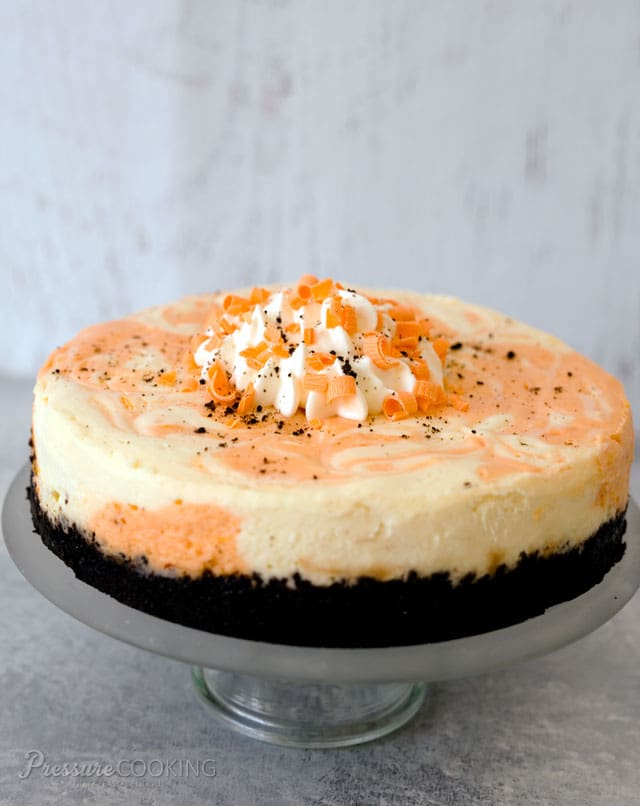 Orange Marble Cheesecake with an Oreo cookie crust on a cake stand