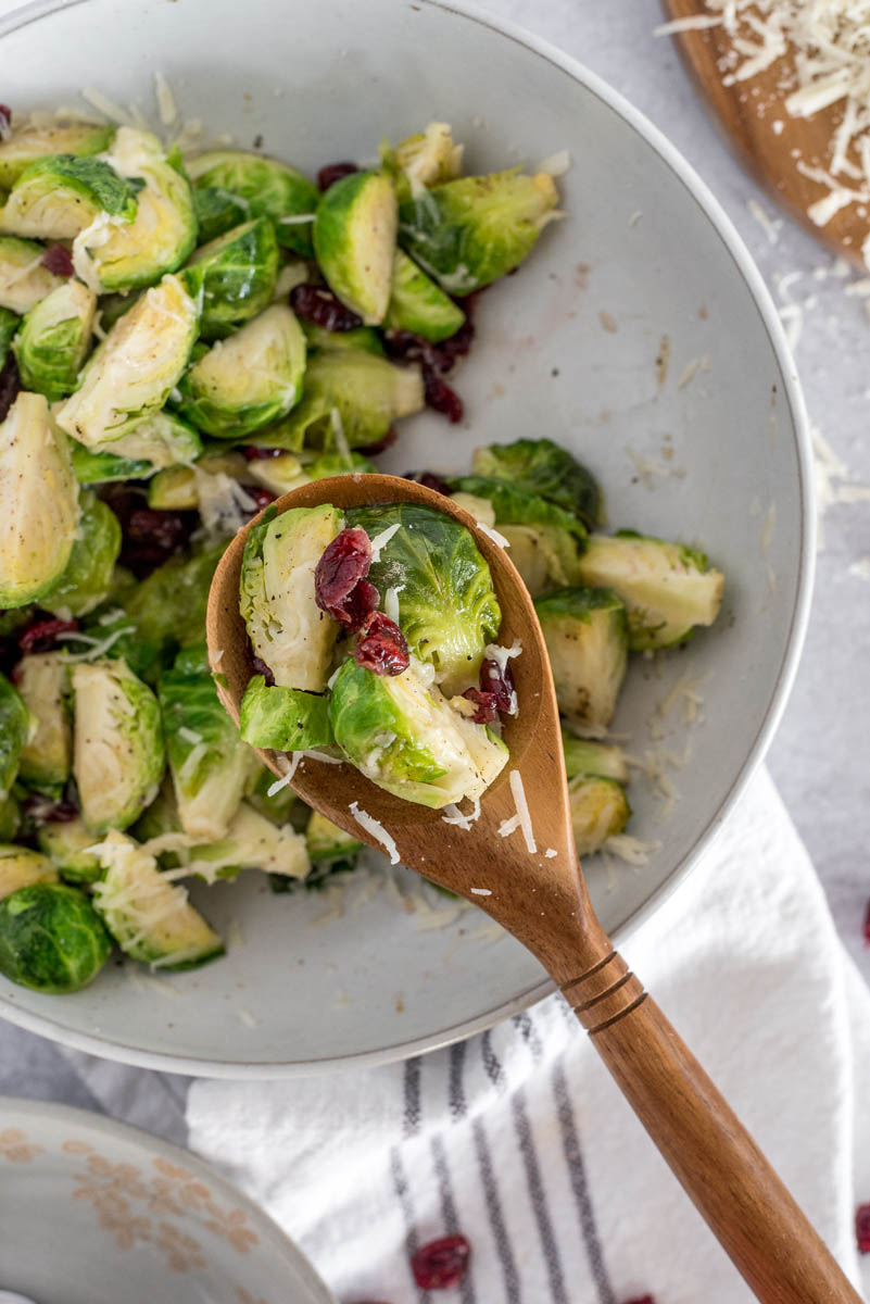 a spoonful of Instant Pot brussels sprouts suspended above a white serving bowl