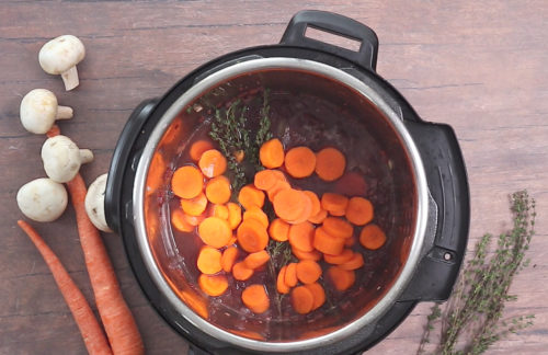 Carrots, red wine, thyme, and broth in the Instant Pot while making Pressure Cooker Coq au Vin