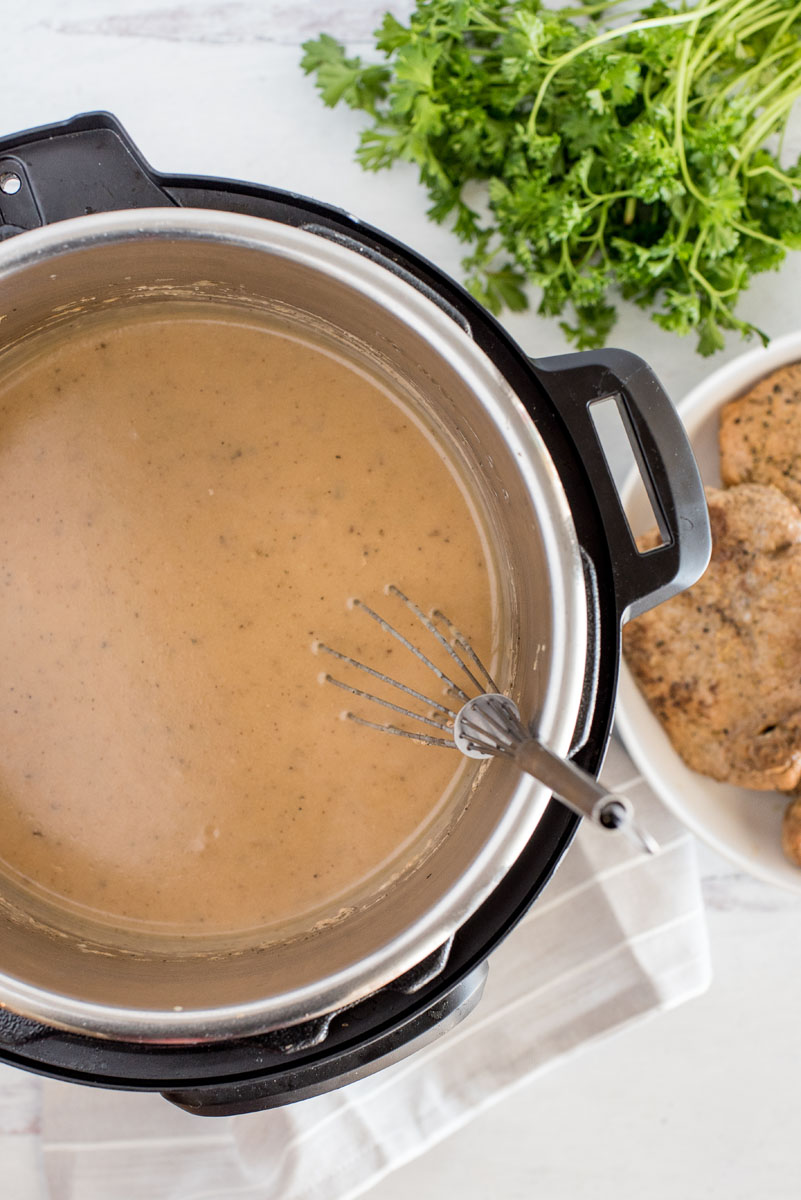 overhead of an instant pot with creamy mushroom gravy being whisked 
