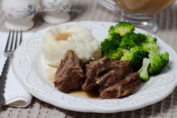 Pressure Cooker Pot Roast served on a white plate with mashed potatoes and broccoli