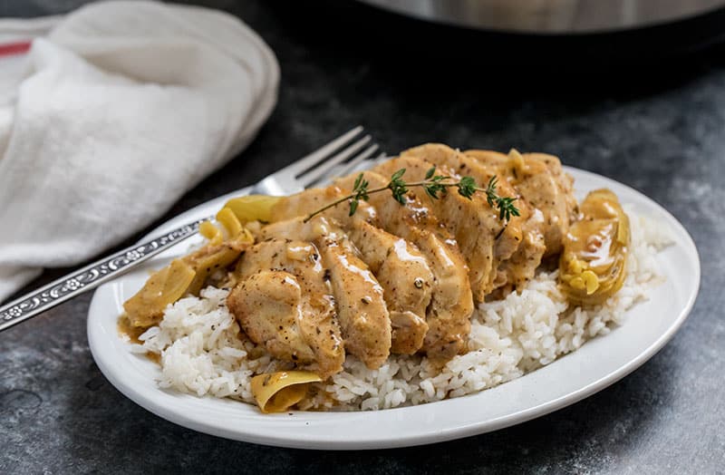 Pressure Cooker (Instant Pot) Artichoke Chicken over rice on a white plate with fork
