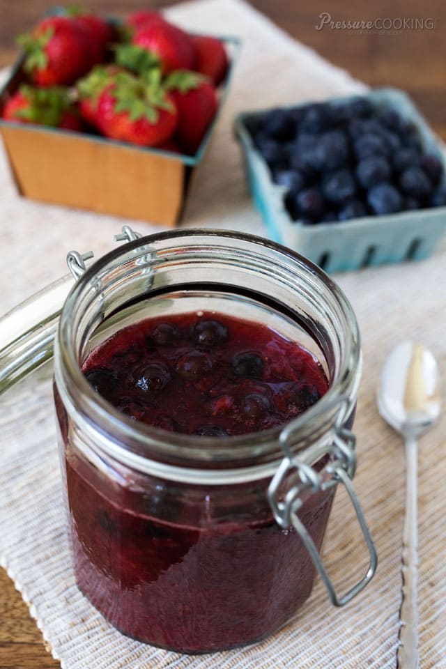 berry compote in a mason jar, with fresh strawberries and blueberries in the background
