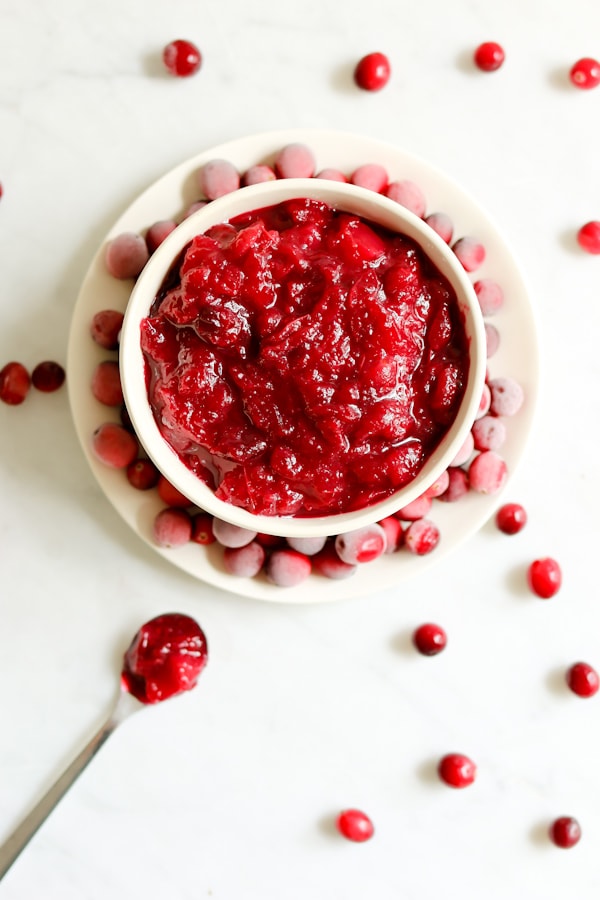 bowl of Pressure Cooker Cranberry Apple Sauce next to a spoon full of the sauce