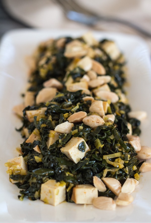 Pressure Cooker Kale with Baked Tofu and toasted almonds on a white serving platter