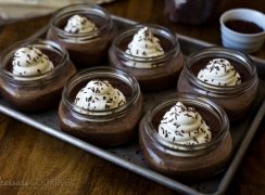 half pint jars filled with Pots de Crème made in an electric pressure cooker, topped with whipped cream and chocolate jimmies