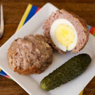 Pressure Cooker (Instant Pot) Scotch Eggs on a white plate with a pickle