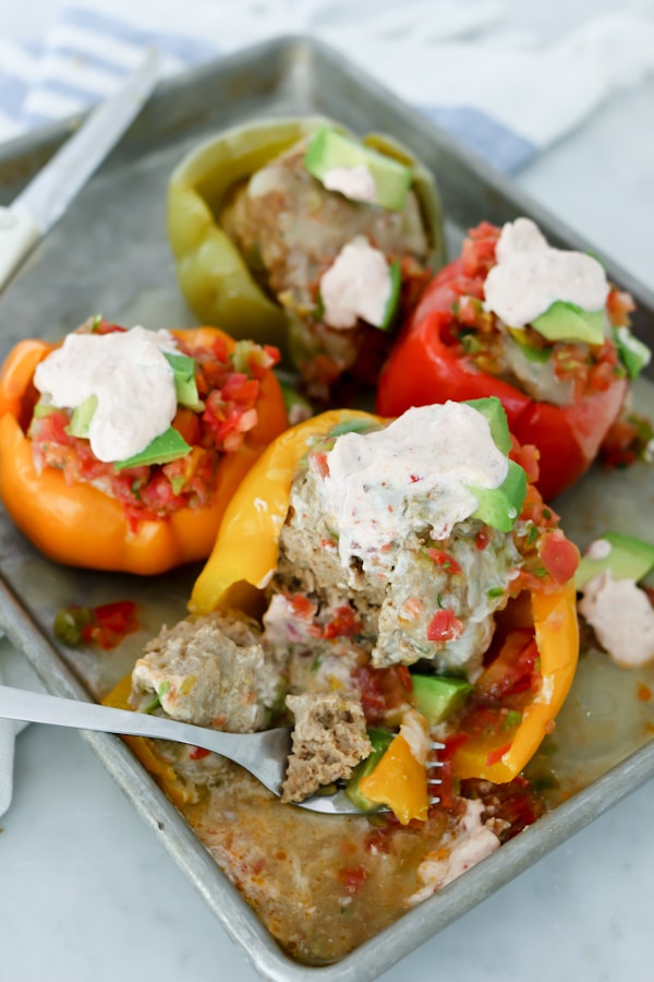 Instant Pot Mexican Stuffed Bell Peppers with Chipotle Lime Sauce - one of the stuffed peppers is being cut with a fork