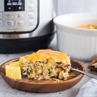 A slice of Pressure Cooker Meat Lovers Crustless Quiche, plated with an Instant Pot in the background
