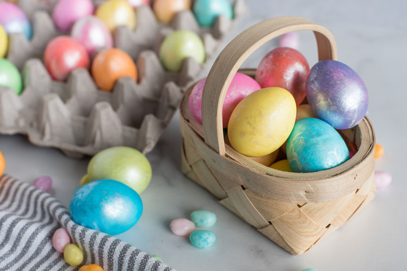 Easter eggs made in an Instant Pot and placed in a basket in front of a carton of Easter eggs.