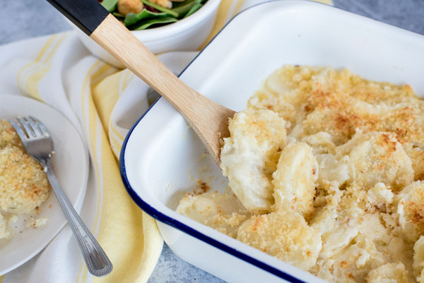 Au gratin potatoes in a serving dish ready to be served. with a wooden spoon
