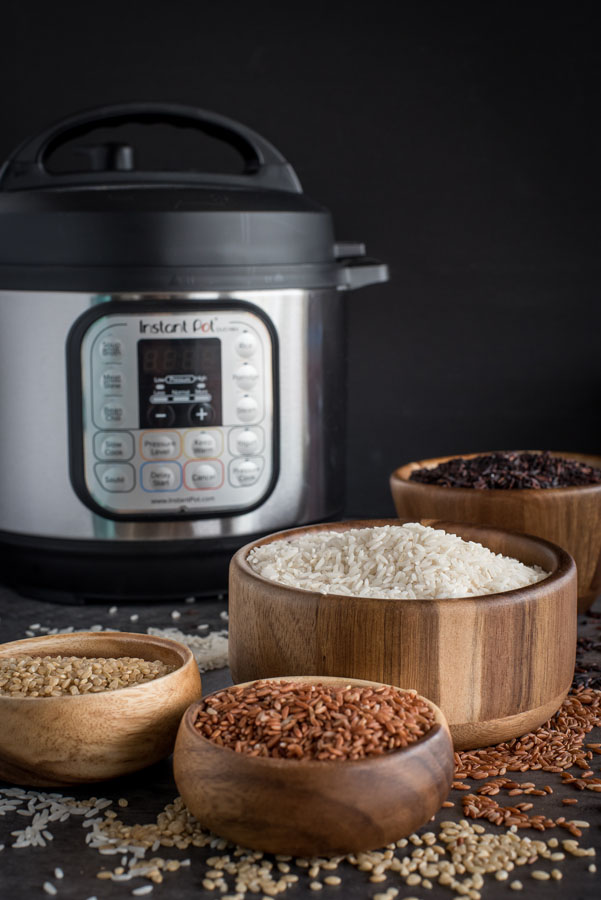 Four wooden bowls of different types of rice with an Instant Pot in the background
