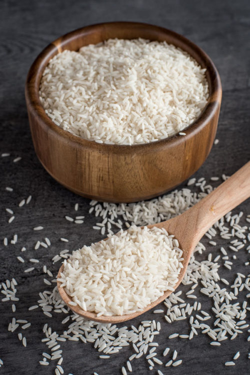 A wooden bowl full of white rice, ready to cook in the pressure cooker