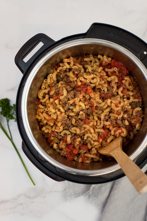 overhead of an instant pot with macaroni noodles, ground beef and tomato sauce to make beefaroni