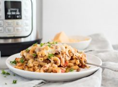 Instant pot american chop suey / beefaroni in front of an electric pressure cooker, with ground beef and mozarella cheese