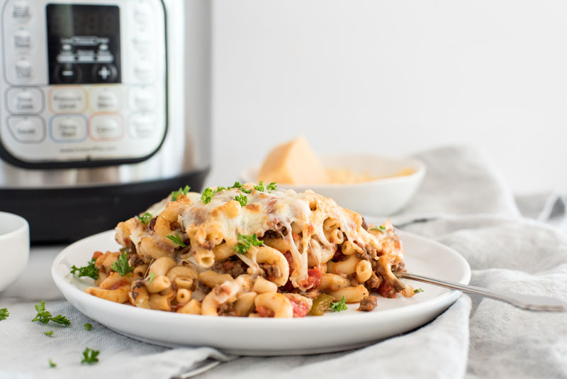 Instant pot american chop suey / beefaroni in front of an electric pressure cooker, with ground beef and mozarella cheese