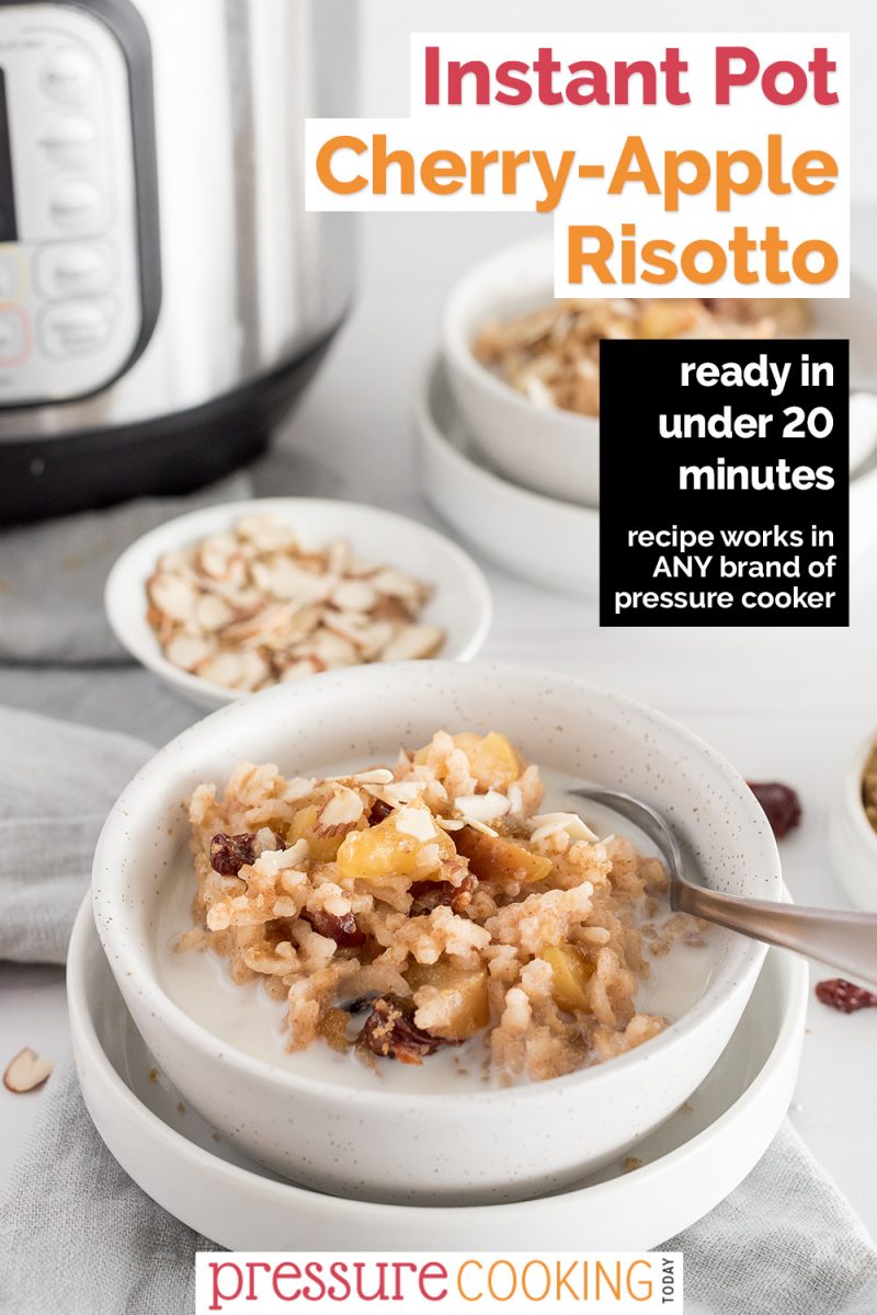 A Pinterest Image that reads "Instant Pot Cherry-Apple Risotto: Ready in under 20 minutes" overlaid on a vertical shot with an Instant Pot and bowls of almonds and cherries in the background with a white speckled bowl filled with breakfast apple risotto, garnished with diced cherries and a splash of milk, with a spoon on the side ready to eat