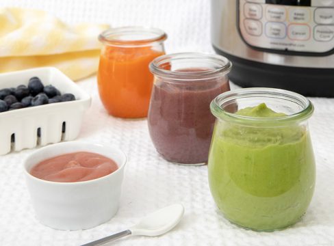 Different colors of Instant Pot baby food puree with an Instant Pot and fresh fruit in the background