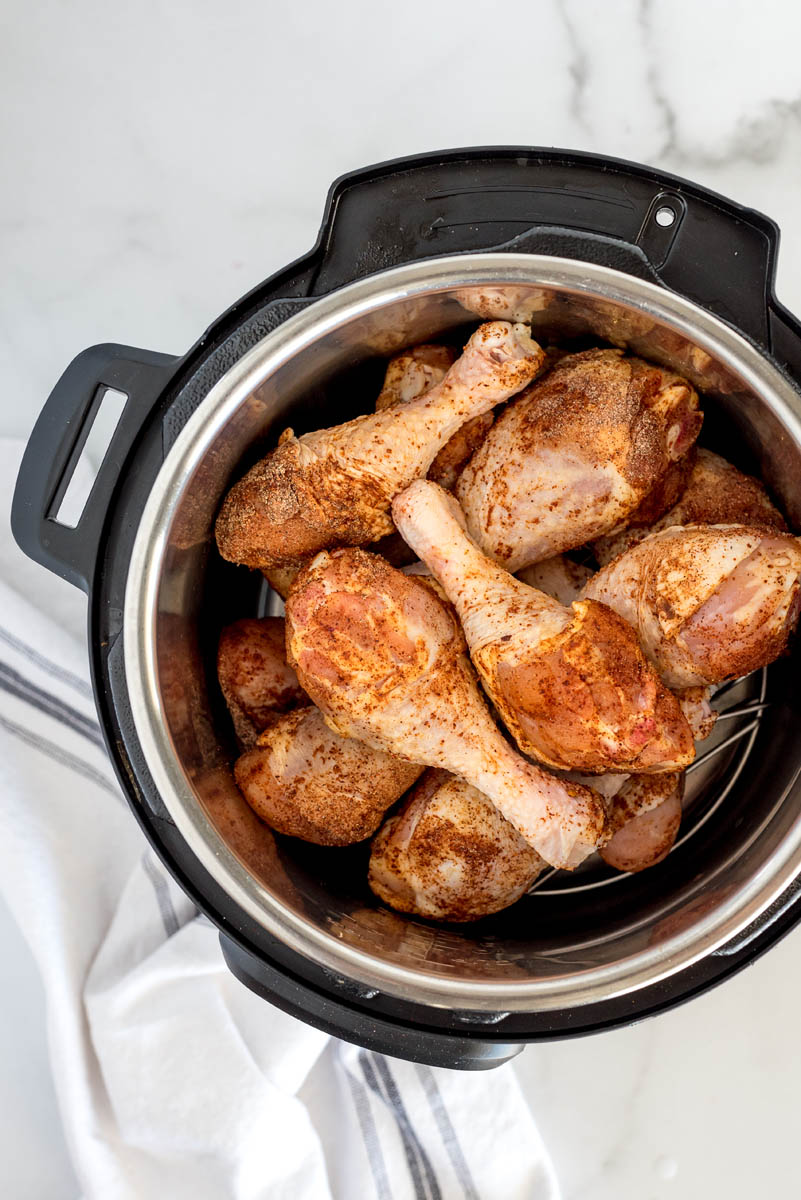 An overhead shot looking down into an Instant Pot filled with chicken legs that are covered in spices