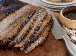 Instant Pot brisket sliced on a cutting board with bbq sauce.